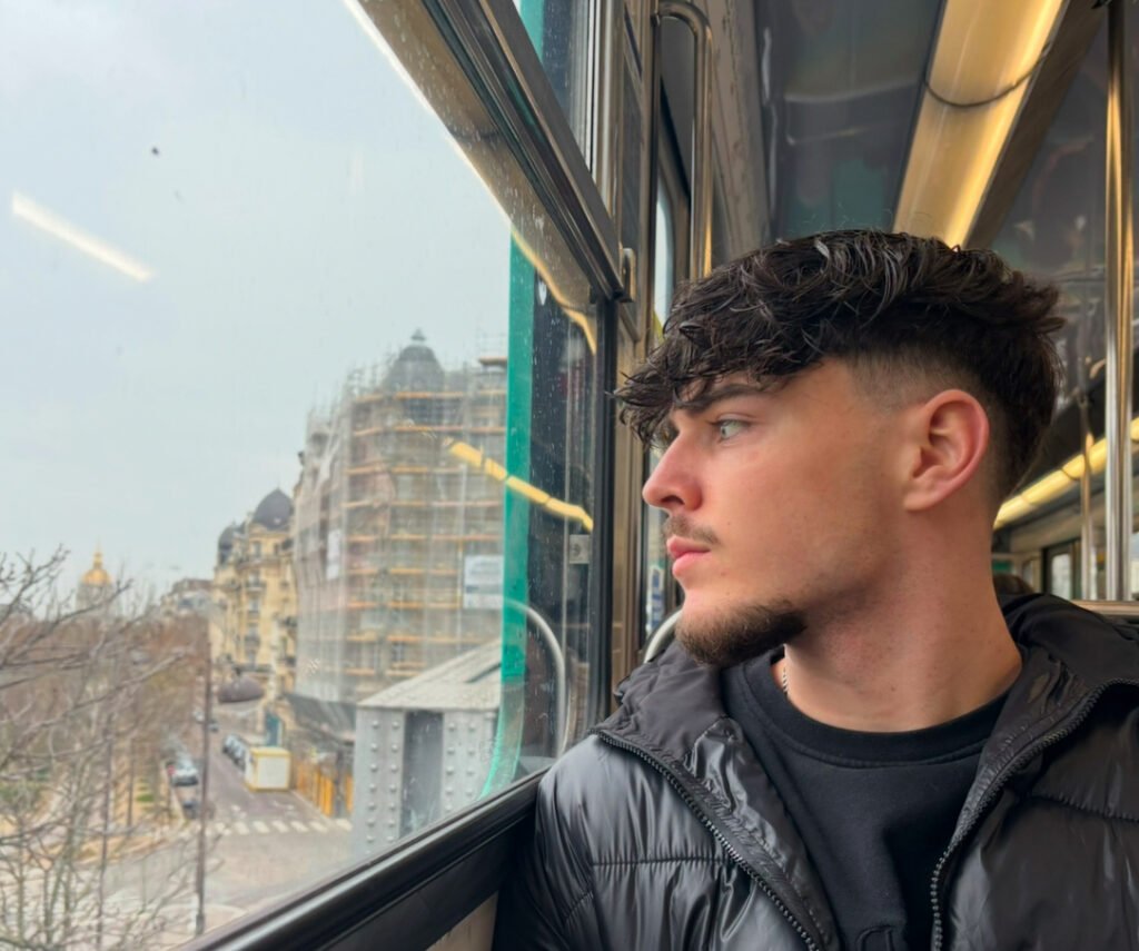 Un jeune homme pensif regardant par la fenêtre d’un bus.